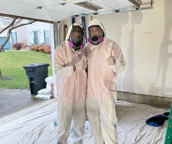 two of our water damage experts wearing their protective suits