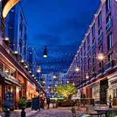 Outdoor shopping street lit with string lights at night.