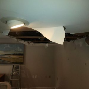 Ceiling collapse with large hole and hanging drywall after severe water damage indoors