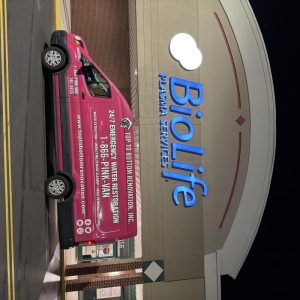 Pink Top To Bottom Renovation service van parked outside BioLife Plasma Services building.