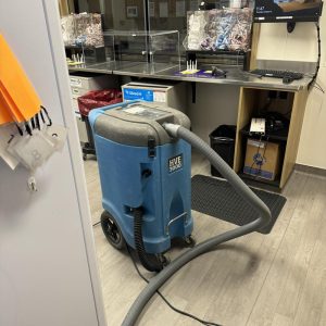 Commercial dehumidifier with hose operating inside an office workspace after water damage.