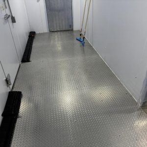 Empty industrial hallway with metal diamond-plate floor.