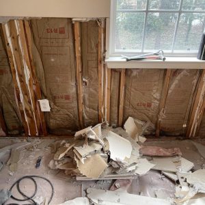Exposed wall insulation and broken drywall debris after water damage removal and restoration work