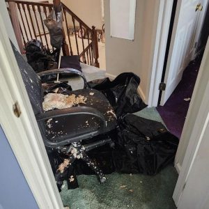 Hallway with debris, damaged chair, and trash bags after ceiling collapse and water damage cleanup