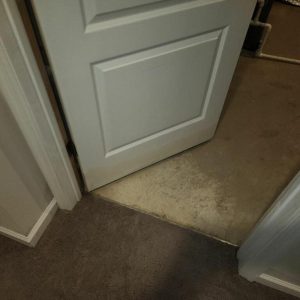 Floor transition area with water-stained subfloor near doorway during restoration work