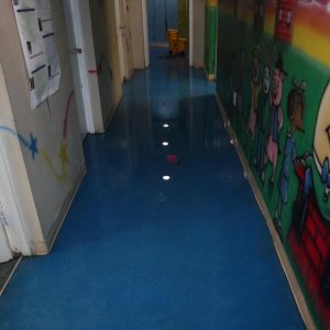 Flooded hallway with standing water on blue floor.