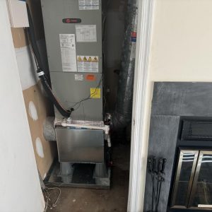 HVAC furnace unit installed in a utility closet beside a fireplace.