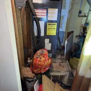 Cluttered utility closet with HVAC unit and debris before cleanup and restoration work