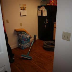Utility room with hardwood floor drying equipment and water extraction hose during restoration process