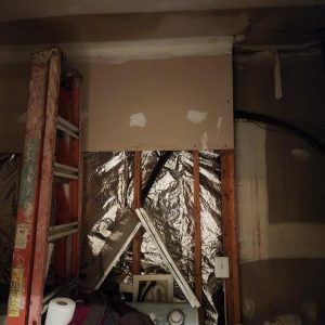 Wall opened with exposed insulation and framing during water damage repair and renovation work