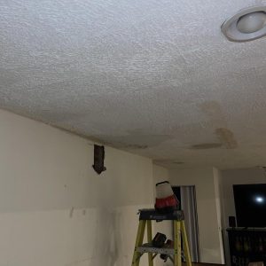 Ceiling with water stains and damaged drywall during indoor water damage repair