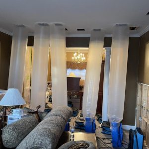 Plastic containment barriers and drying equipment set up in living room during water damage restoration