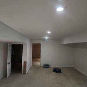 Finished basement with recessed lighting and carpet after restoration and cleanup work