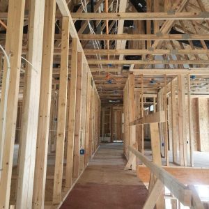 Basement framing stage showing newly constructed wooden stud walls and ceiling joists during home renovation and structural rebuild work
