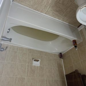 Bathtub filled with standing water in a tiled bathroom, showing signs of a plumbing or water backup issue.