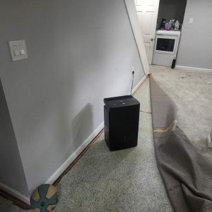 Dehumidifier drying carpeted basement area after water damage.