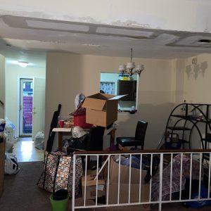 Living room with ceiling water damage and belongings piled during home restoration work
