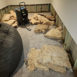 Basement insulation removed and piled on floor during water damage remediation process