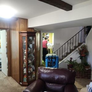 Living room with drying equipment and technician working in adjacent area during water damage restoration