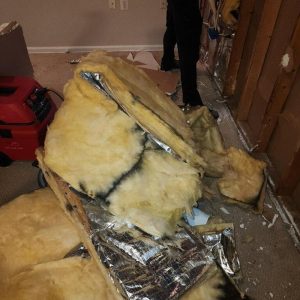 Removed mold-contaminated insulation piled on floor during basement remediation work