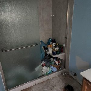 Bathroom shower area with flooring removed and visible water damage near the base after restoration work.