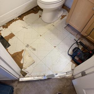 Bathroom floor with damaged vinyl tiles removed.