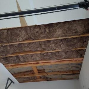 Ceiling with exposed wooden joists and insulation after drywall removal.