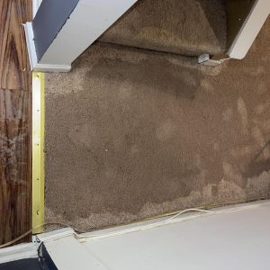 Wet carpet at doorway with visible water stains during indoor flood damage cleanup