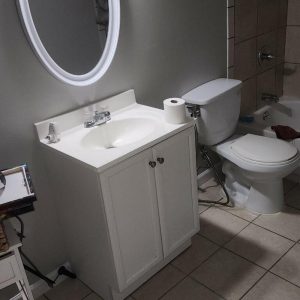Bathroom with vanity, toilet, and tiled floor after water damage repair and restoration