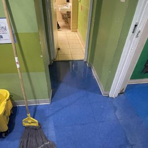 Wet hallway floor transitioning to tiled room during cleanup.