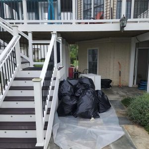 Exterior cleanup with black debris bags and plastic sheeting outside home during water damage restoration