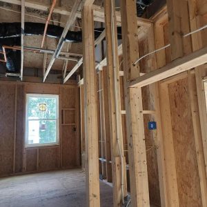 Interior framing of new home with exposed studs, wiring, and window during construction phase