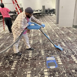 Technician extracting water from carpet in a commercial space.
