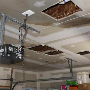 Garage ceiling with water-damaged drywall and exposed openings.