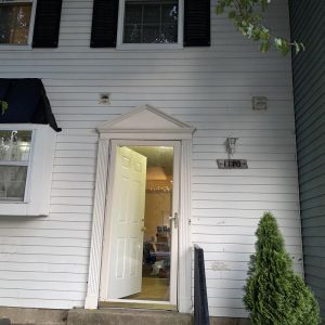 Front entrance of residential home with open door during property restoration visit