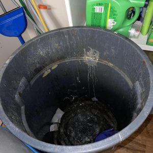 Trash bin filled with contaminated water and debris during indoor water damage cleanup process