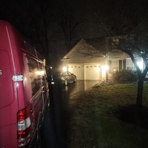 Restoration service van parked outside residential home at night during emergency response