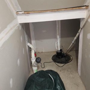 Sump pump system and plumbing in unfinished basement closet during water damage repair