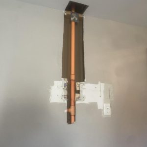 Exposed copper plumbing pipe inside wall after drywall removal during water damage repair