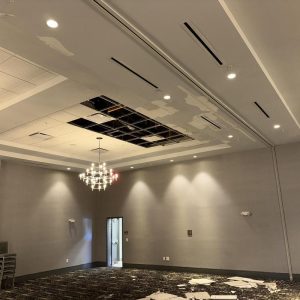 Commercial room with damaged ceiling tiles and water damage.