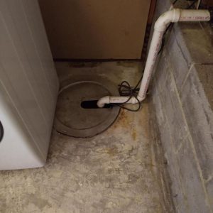 Basement sump pit and drain system with signs of water intrusion and moisture damage during flood cleanup and water damage restoration