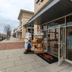 Storefront with a person carrying boxes near the entrance.